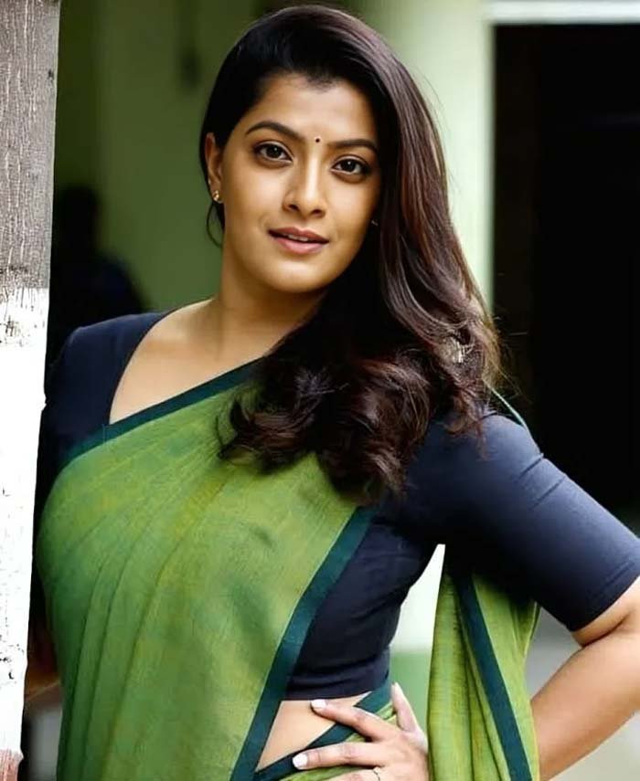 South Indian actress Varalaxmi Sarathkumar posing in a green cotton saree with a dark blue blouse.